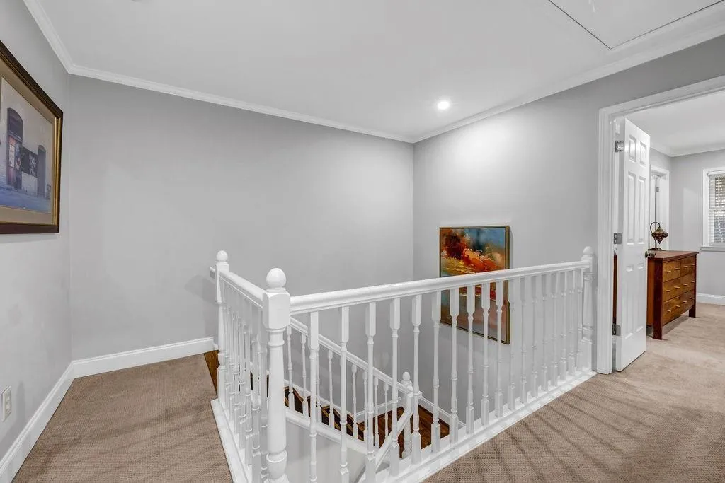 Hallway with crown molding, an upstairs landing, baseboards, and carpet floors