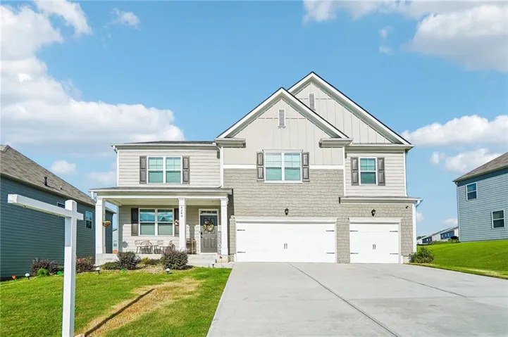 Multilevel residence featuring a covered front porch, a two-car garage, and a concrete driveway