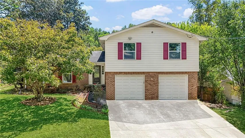 Two-story residence featuring brick and siding facade, red window shutters, a two-car garage, and a concrete driveway