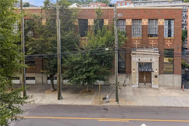 Brick facade building featuring a stone entryway with double doors, large multi-pane windows, and decorative brickwork