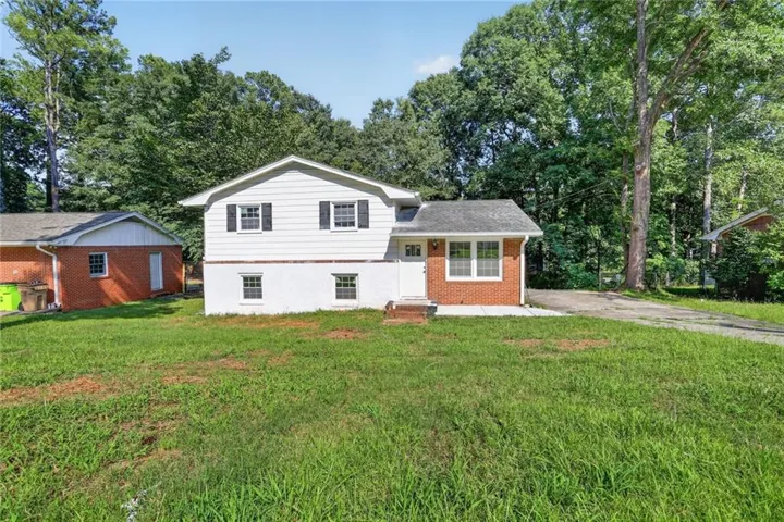Split-level home featuring white siding, brick accents, and a front entry