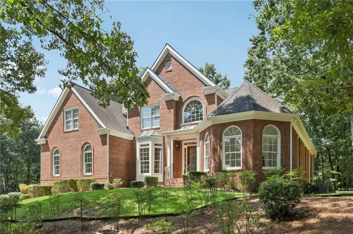 Brick exterior residence featuring a covered entry, arched windows, gabled rooflines, and a turret-style architectural element