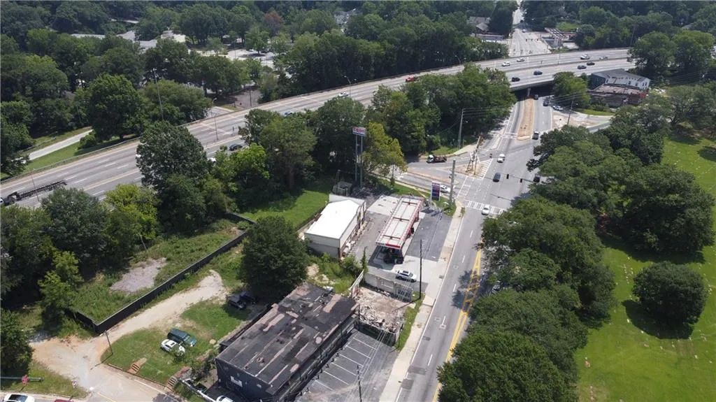 Aerial view of property and surrounding area featuring a major roadway and a tree filled landscape