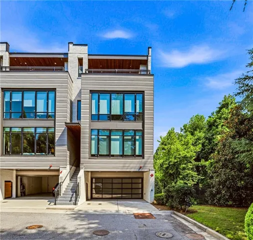 Modern architectural design featuring expansive fenestration, multiple private garage bays, and rooftop deck spaces with wood-finish decking