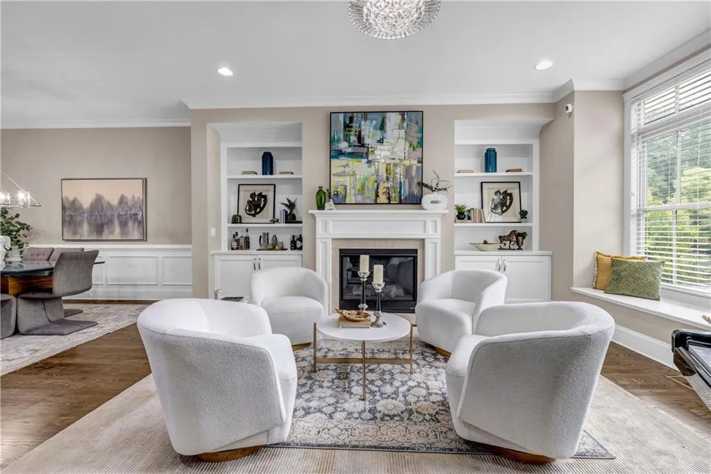 Living area with a chandelier, ornamental molding, a glass covered fireplace, wood finished floors, and recessed lighting