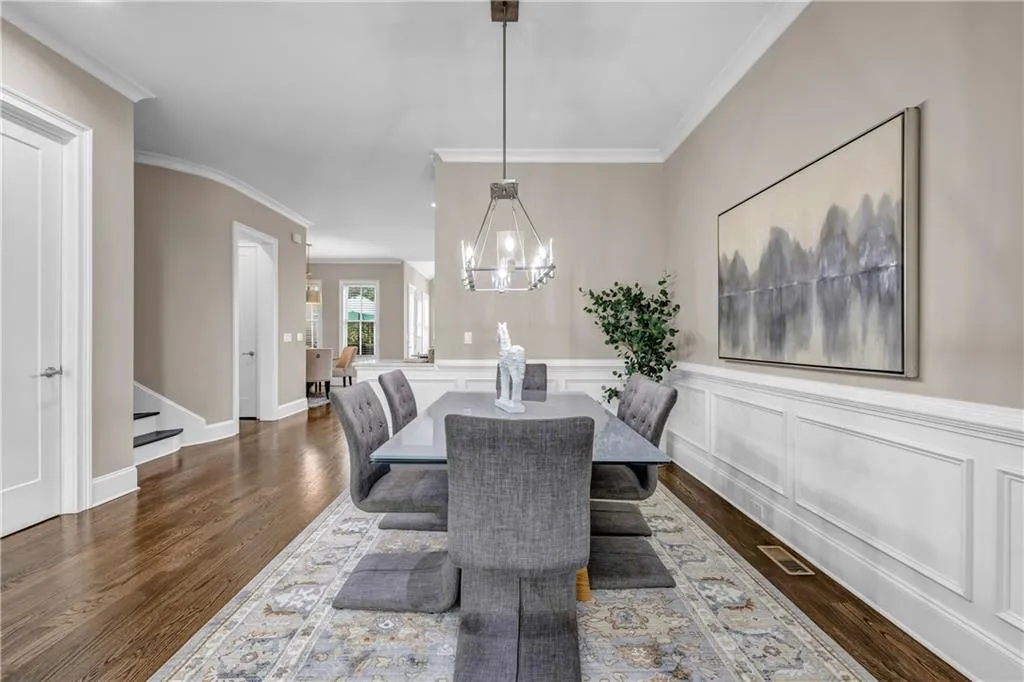 Dining space featuring stairs, crown molding, dark wood-style flooring, a chandelier, and wainscoting