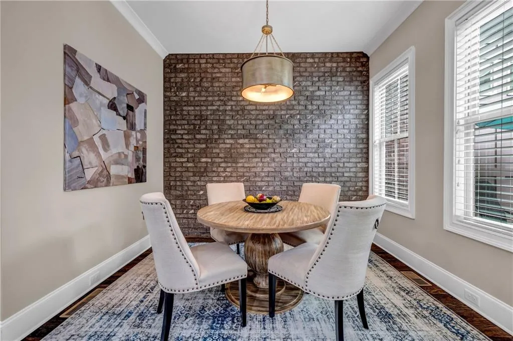Dining area featuring brick wall, dark wood-type flooring, an accent wall, and ornamental molding