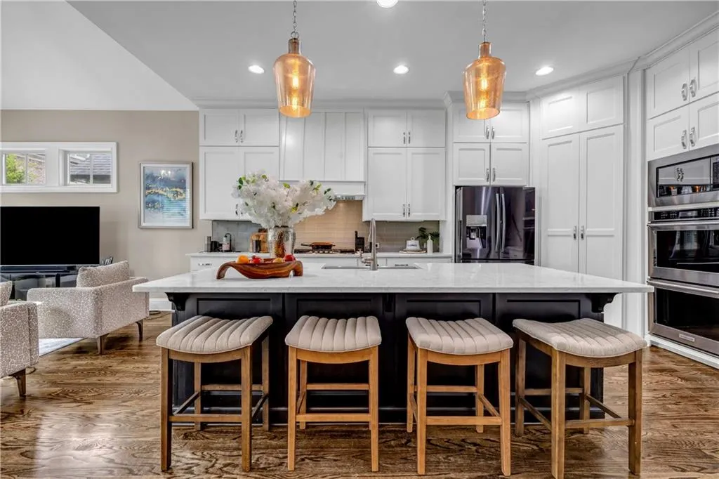 Kitchen featuring a kitchen bar, white cabinets, dark wood-type flooring, stainless steel appliances, and recessed lighting
