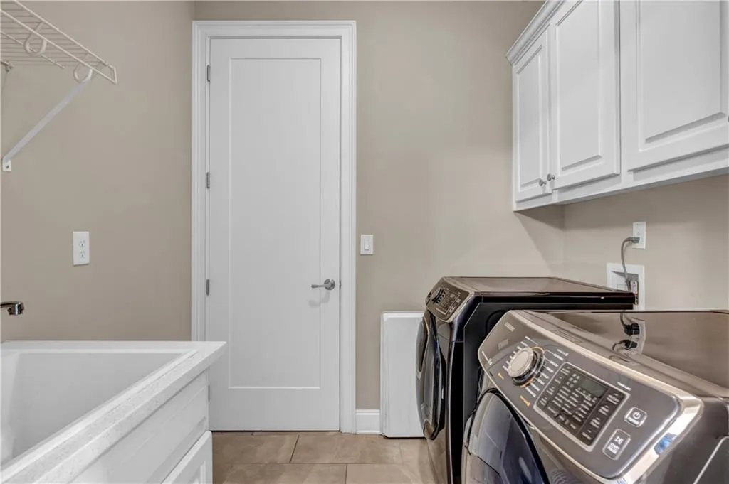 Laundry area featuring light tile patterned flooring, washer and clothes dryer, and cabinet space