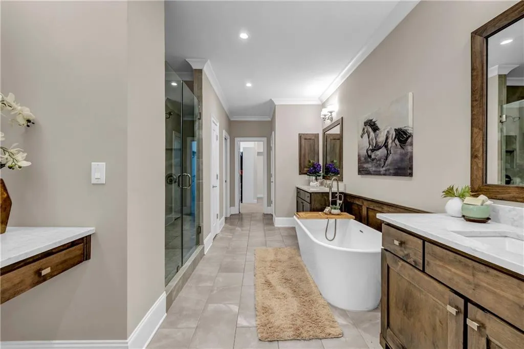 Full bath featuring a soaking tub, two vanities, crown molding, a shower stall, and recessed lighting