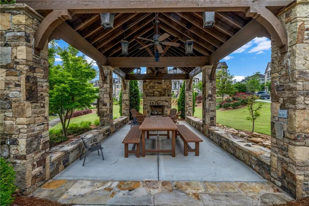 View of patio / terrace with an outdoor stone fireplace, ceiling fan, and outdoor dining space