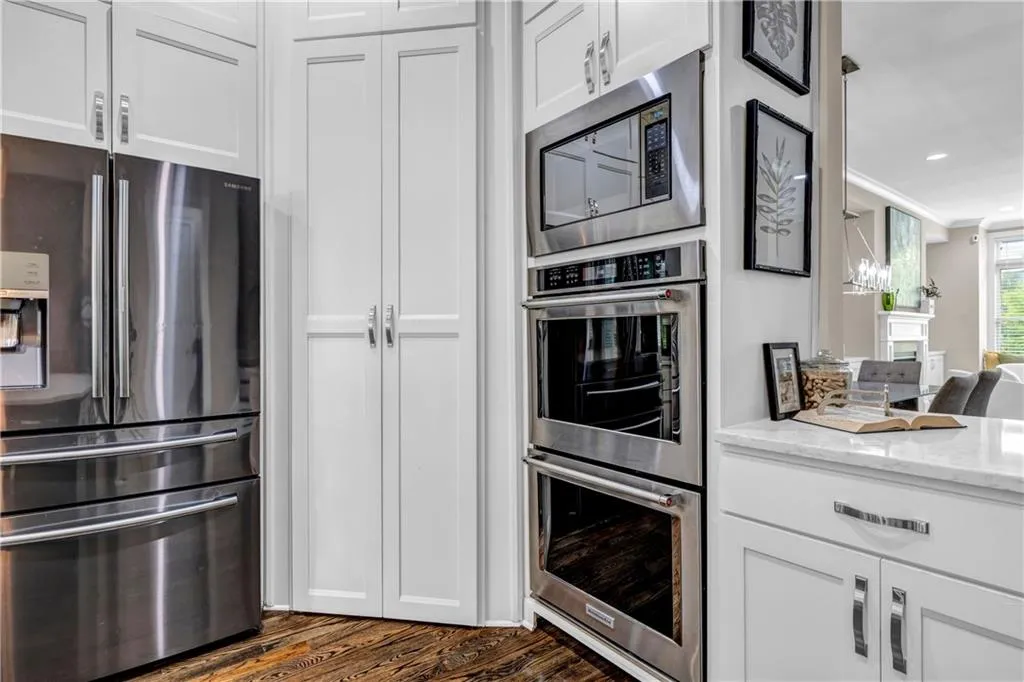 Kitchen featuring stainless steel appliances, white cabinetry, light stone counters, dark wood-type flooring, and recessed lighting