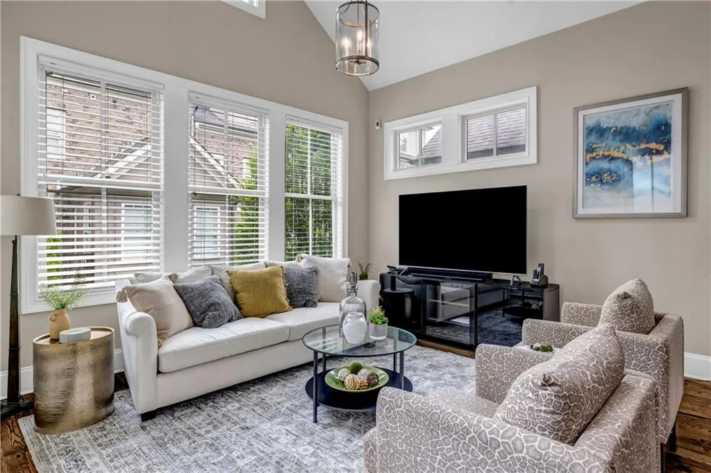 Living room with lofted ceiling, plenty of natural light, wood finished floors, and a chandelier