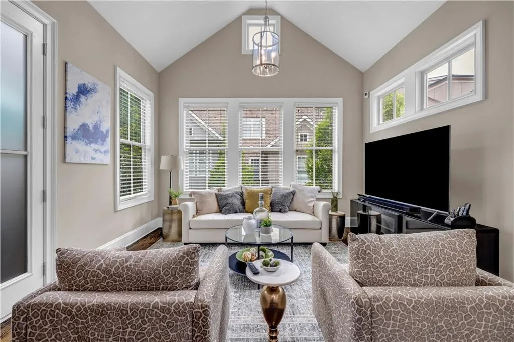 Living room with plenty of natural light, lofted ceiling, and a chandelier