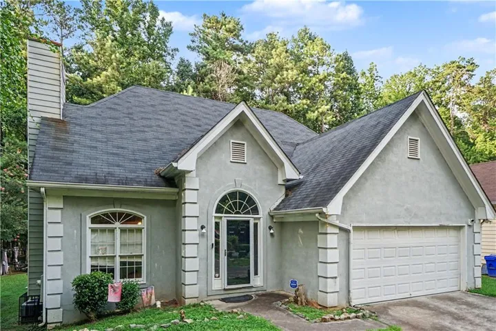 Stucco exterior with an arched entry, a prominent two-car garage, and an attached chimney feature