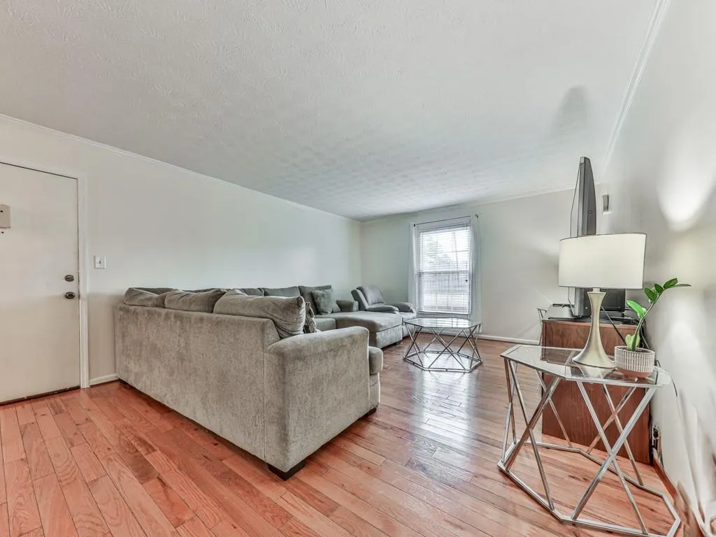 Living room featuring ornamental molding, light wood finished floors, and a textured ceiling