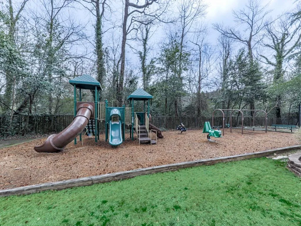 View of community play area featuring a play set with slides and swings