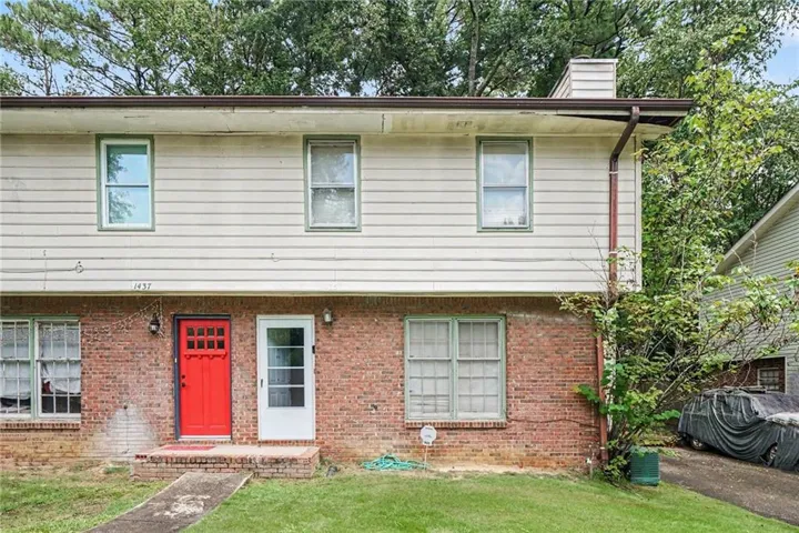 Brick and siding exterior with a bright red front door
