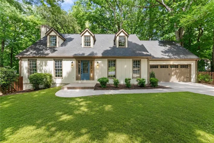 Exterior with dormer windows, a prominent front entry, attached garage, and a concrete driveway