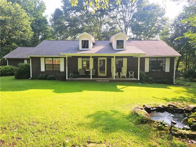 Brick exterior with a covered front porch, white columns, and twin dormer windows