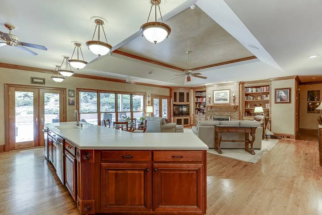 Kitchen featuring light wood-type flooring, a kitchen island, a large fireplace, and ceiling fan