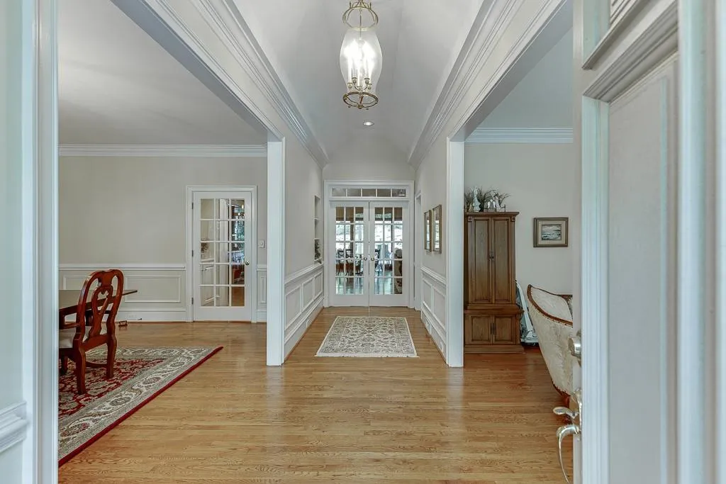 Entryway with ornamental molding, light hardwood / wood-style flooring, french doors, and a notable chandelier