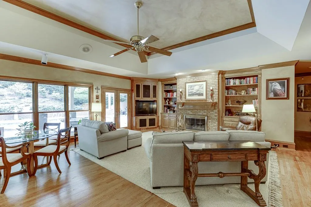 Living room featuring light hardwood / wood-style floors, a raised ceiling, a fireplace, and ceiling fan