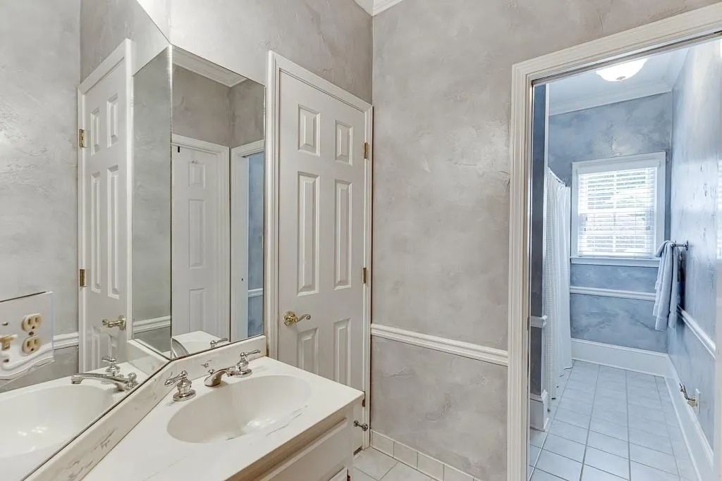Bathroom with tile patterned floors, vanity, and crown molding