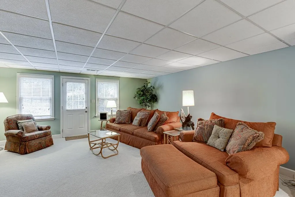 Carpeted living room featuring a drop ceiling