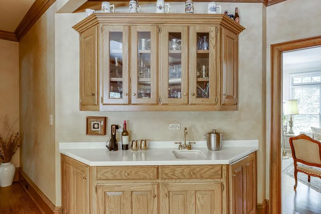 Bar with sink, light brown cabinets, hardwood / wood-style flooring, and crown molding