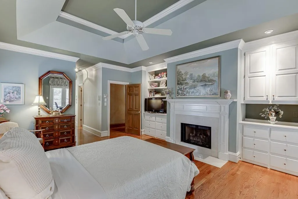 Bedroom with crown molding, light hardwood / wood-style floors, a tray ceiling, and ceiling fan