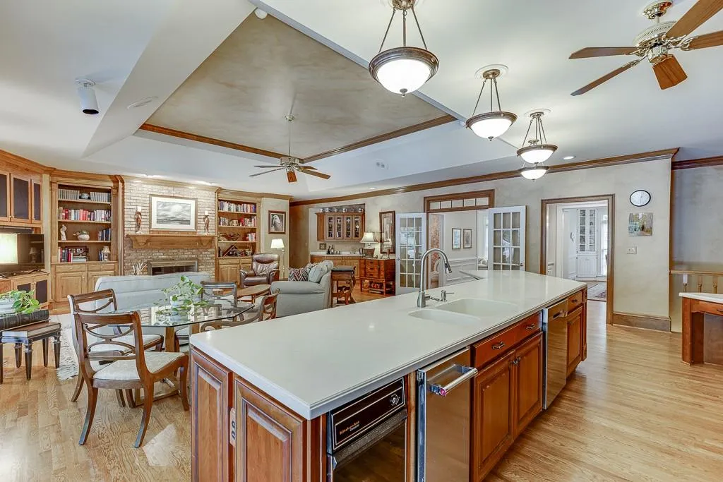Kitchen with sink, an island with sink, a fireplace, decorative light fixtures, and ceiling fan