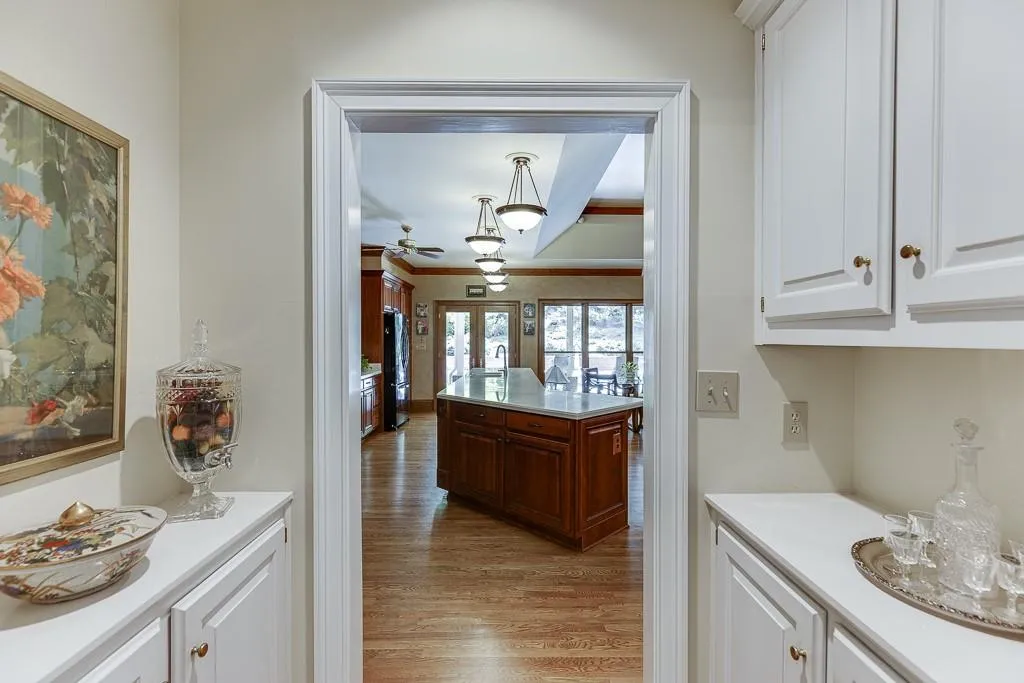 Kitchen featuring light hardwood / wood-style flooring, white cabinetry, black refrigerator, and decorative light fixtures