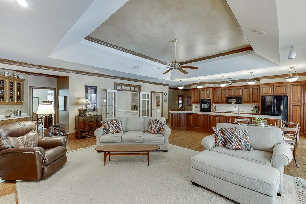 Living room featuring ceiling fan, a raised ceiling, sink, and light hardwood / wood-style flooring