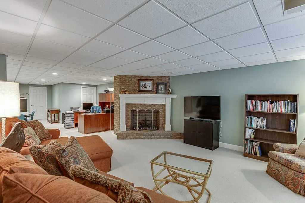 Carpeted living room with a drop ceiling and a brick fireplace