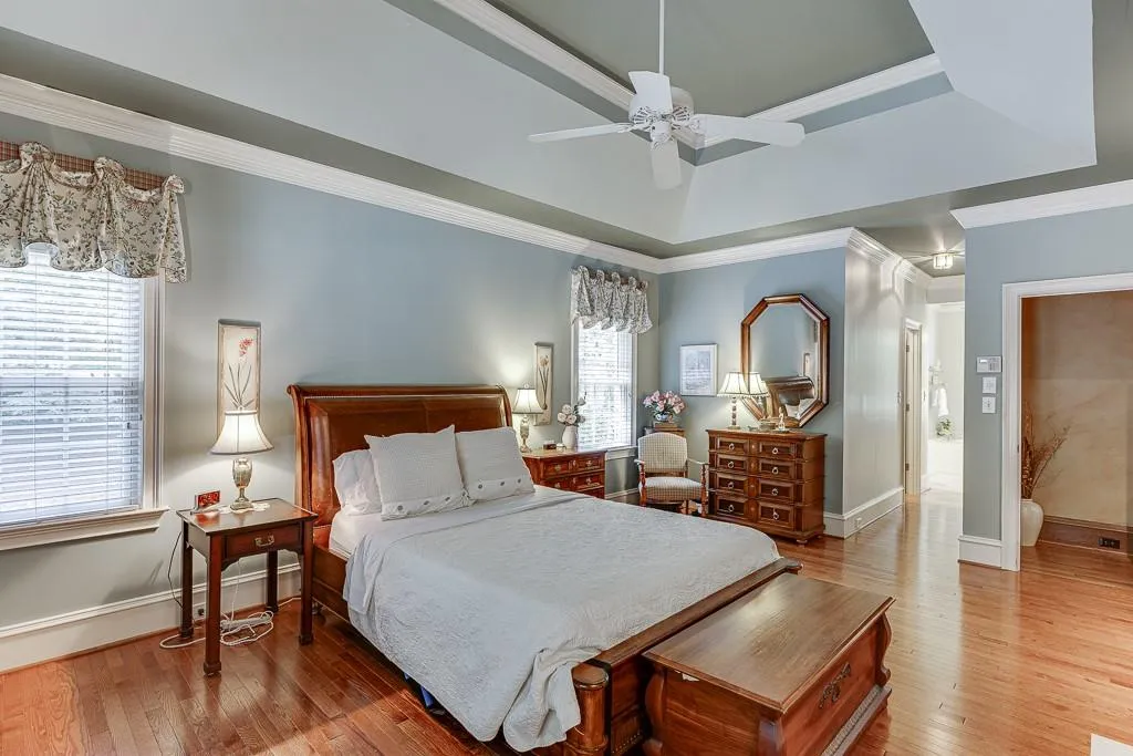 Bedroom with wood-type flooring, a tray ceiling, crown molding, and ceiling fan