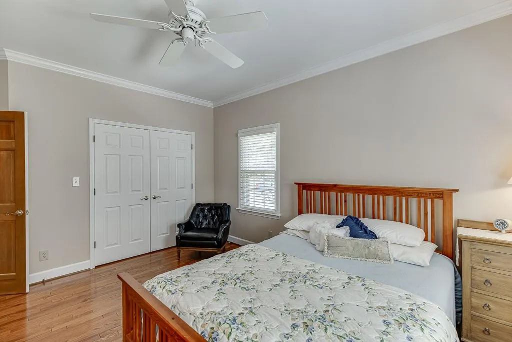 Bedroom with a closet, light wood-type flooring, ceiling fan, and crown molding