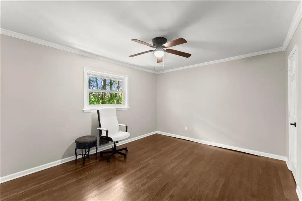 Unfurnished room with ornamental molding, dark wood-type flooring, and a ceiling fan