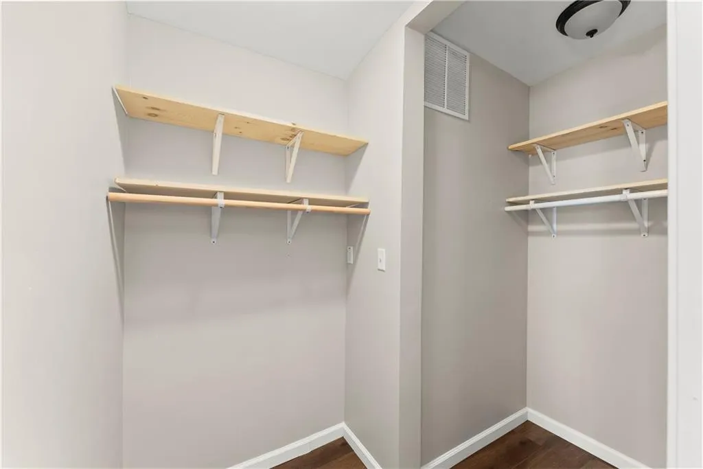 Walk in closet with dark wood-style floors