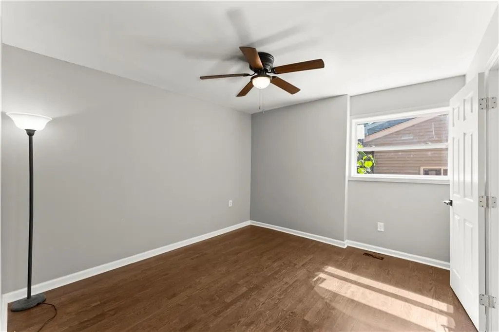Unfurnished room with dark wood-style floors and ceiling fan