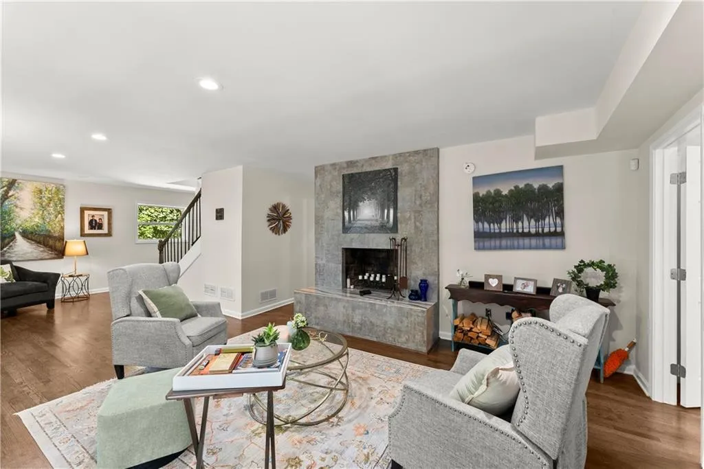 Living room with wood finished floors, a tiled fireplace, and recessed lighting
