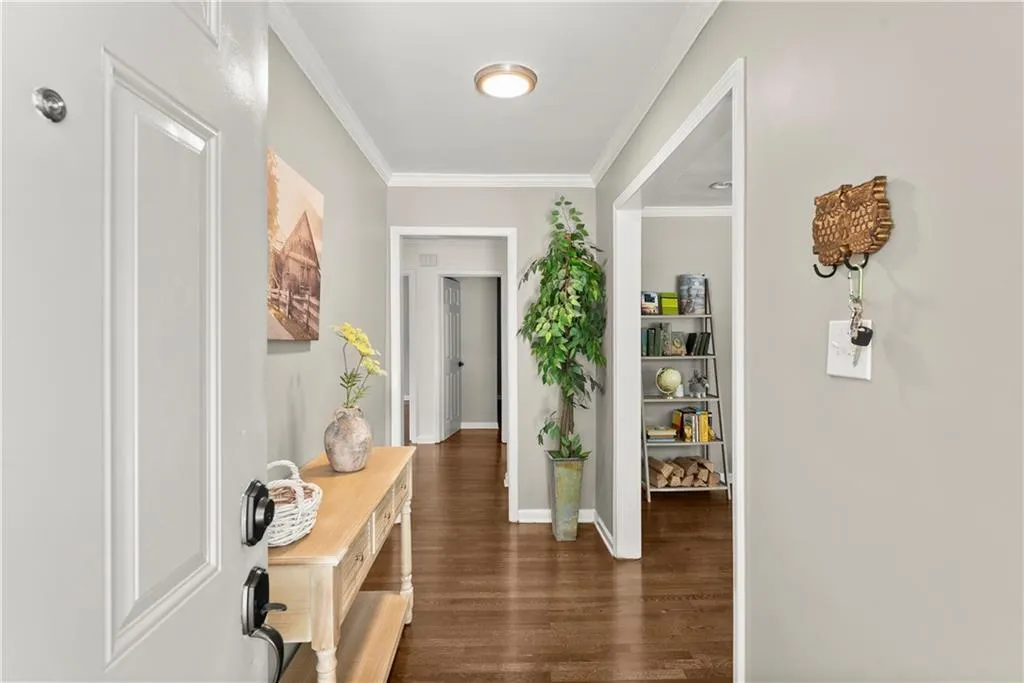 Hall featuring ornamental molding and dark wood-type flooring
