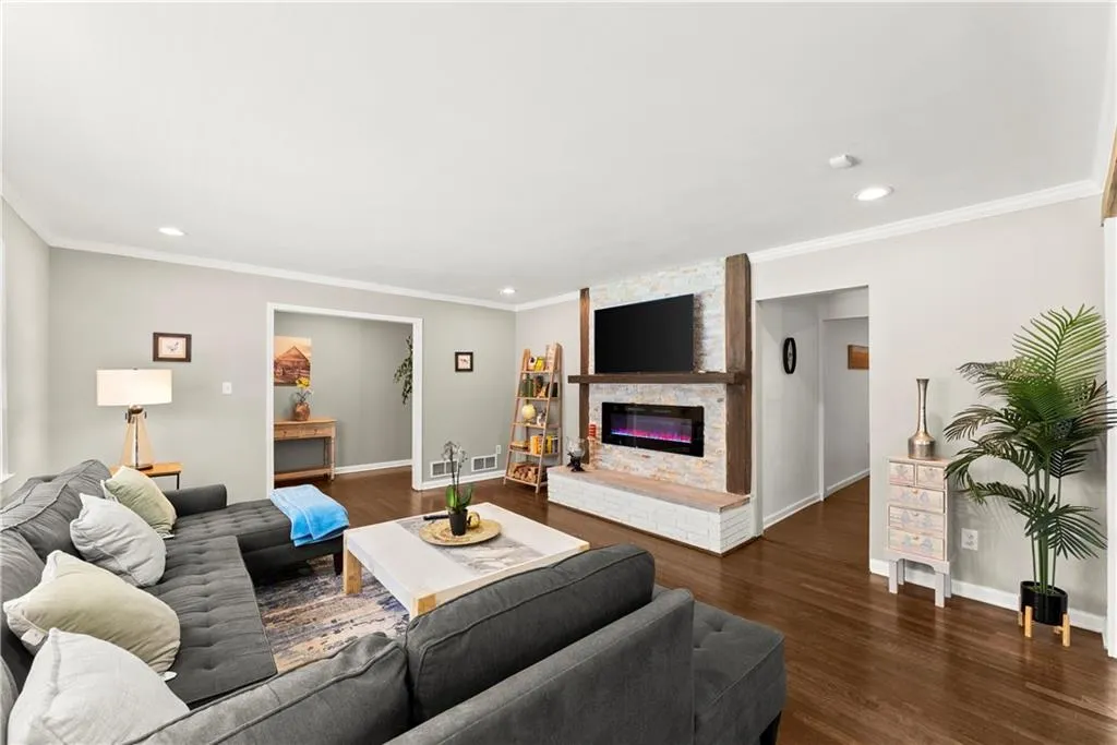 Living area featuring recessed lighting, dark wood-type flooring, crown molding, and a fireplace