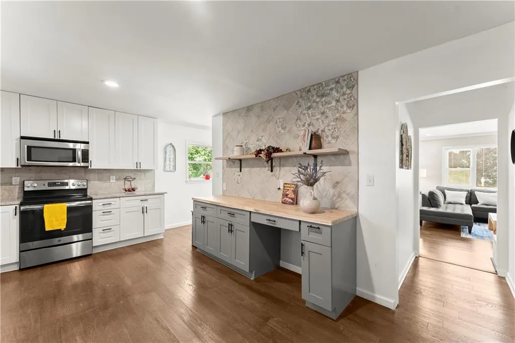 Kitchen featuring open shelves, stainless steel appliances, backsplash, dark wood finished floors, and butcher block countertops