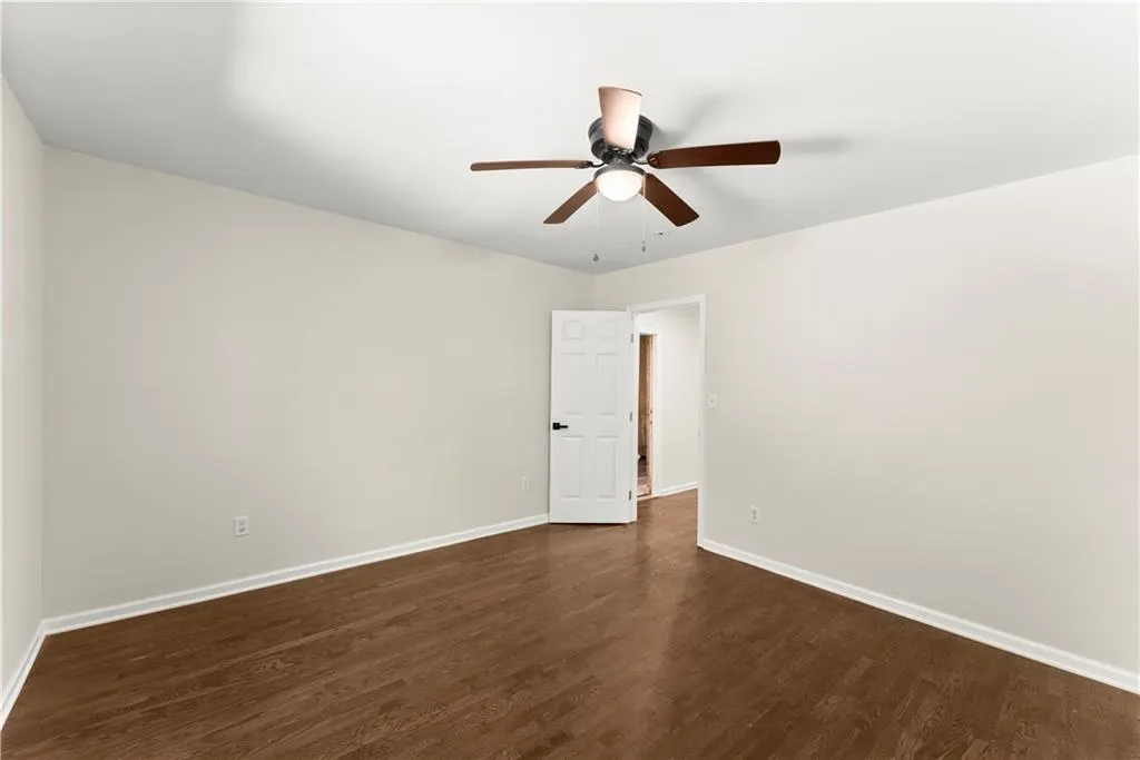 Spare room featuring dark wood-style flooring and ceiling fan