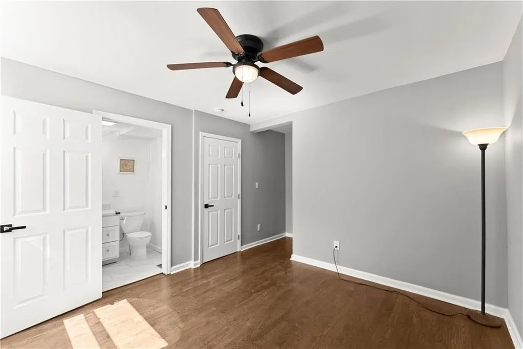 Unfurnished bedroom featuring wood finished floors, ceiling fan, and connected bathroom