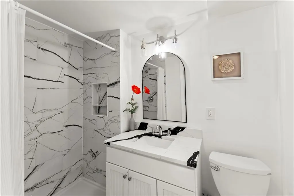 Bathroom featuring vanity and a marble finish shower