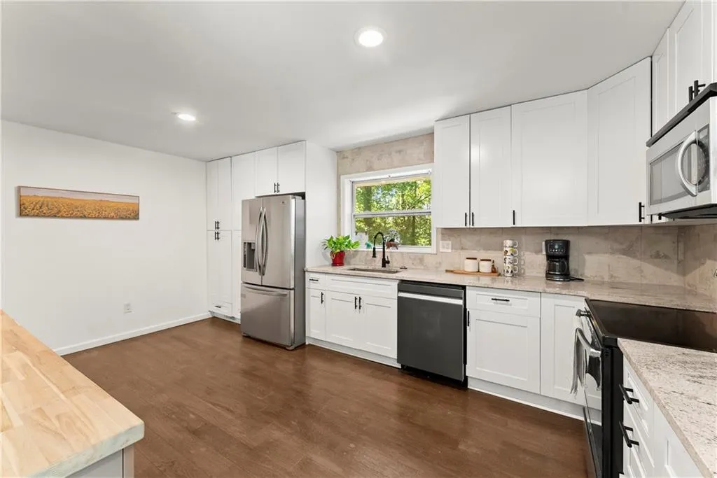 Kitchen with appliances with stainless steel finishes, white cabinetry, backsplash, dark wood-style flooring, and recessed lighting