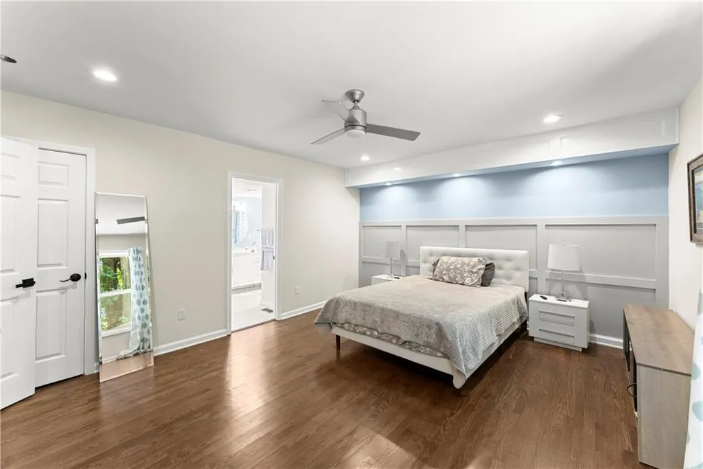 Bedroom featuring dark wood-style floors, a ceiling fan, recessed lighting, a decorative wall, and ensuite bathroom