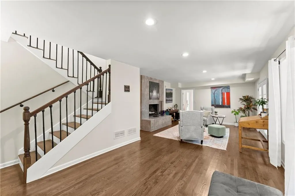 Living room with a tile fireplace, recessed lighting, dark wood-type flooring, and stairs